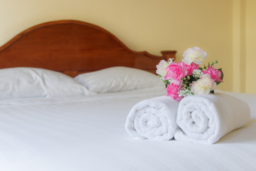 Fototapeta na wymiar Flower with towel on bed in hotel room