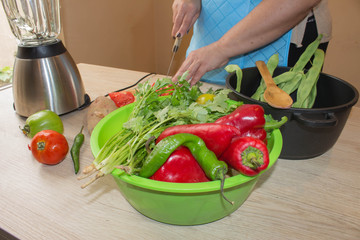 Chef cuts the vegetables into a meal. Preparing dishes. A woman uses a knife and cooks. Woman's hands cooking healthy meal in the kitchen, behind fresh vegetables