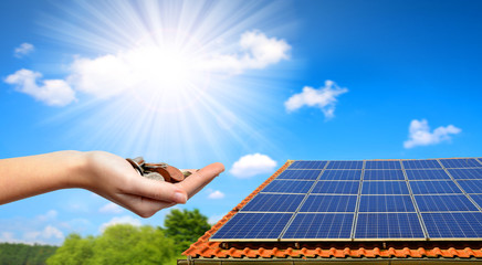 Solar panel on the roof of the house and coins in hand. The concept of money saving and clean...