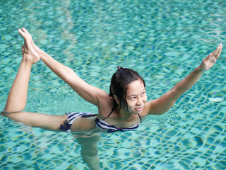 professional asian woman practice yoga sequence standing bow pulling pose close up in swimming pool, aqua yoga blue water