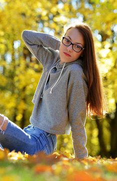 Girl with glasses in autumn park.