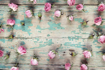 Frame of dried rose flowers on the turquoise old wooden background with copy space. Flat lay, top...