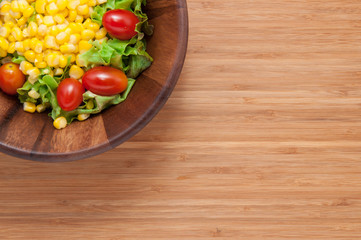 Corn salad in bowl on wooden table.