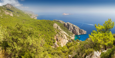 Fototapeta na wymiar Idyllic Mediterranean landscape with a solitary bay of azure color and mountains covered with pine forest, travel in paradise concept