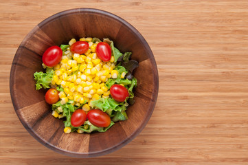 Corn salad in bowl on wooden table.