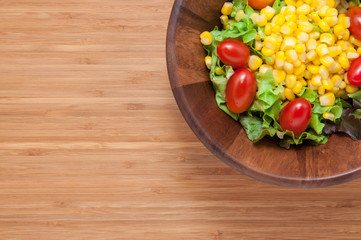 Corn salad in bowl on wooden table.