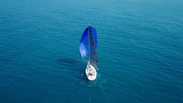 Small yacht with large open blue sail
