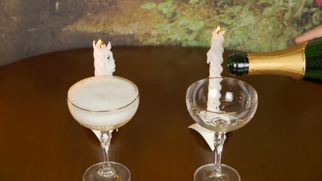 Romantic evening. A man's hand bottles champagne with wine. Candles are burning. Quiet and cozy evening. In anticipation of the holiday.