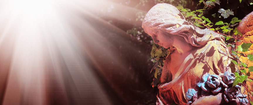 Majestic view of statue of golden angel illuminated by sunlight against a background of dark background. Dramatic unusual scene. Retro filter and vintage style.