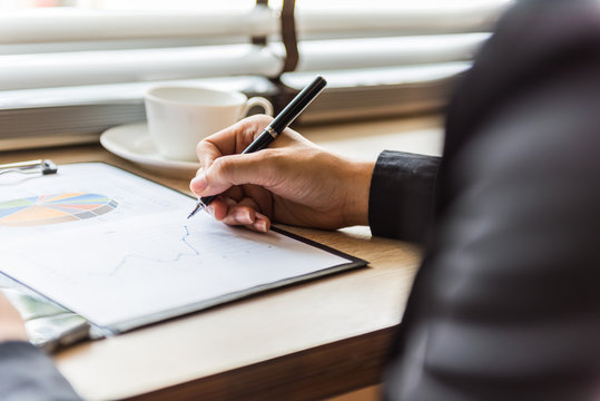 businessman working on documents graphic concentrated with pen on the table at office.