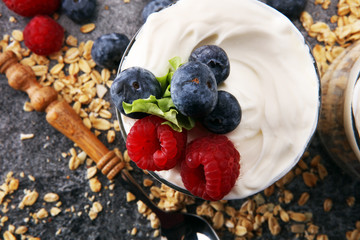 Glass jar of homemade granola with yogurt and fresh berries