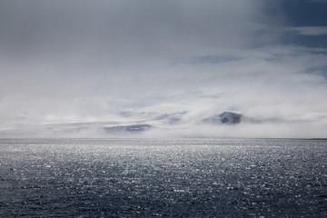 Wind and clouds sweep over this mountain in Antarctica. © robert
