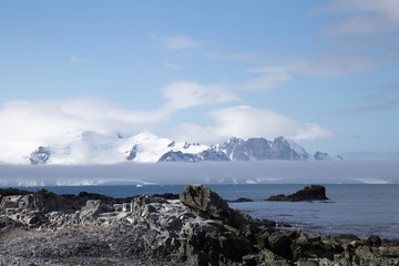 A mountain top reaches over the mist and clouds in Antarctica.