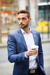 businessman standing in the street holding a cup
