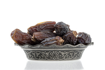 Dried dates in vintage plate isolated on white background.