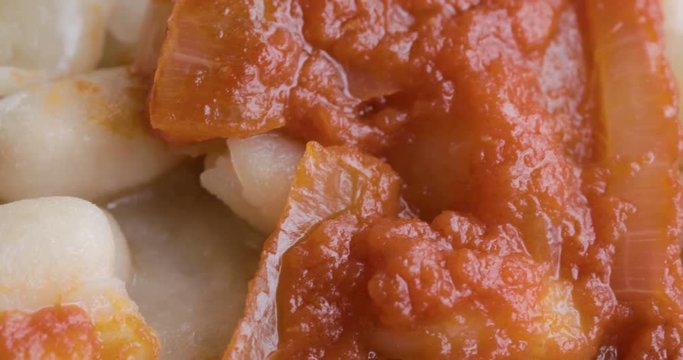 Fagioli bianchi con salsa al pomodoro piccante e cipolla su un piatto nero