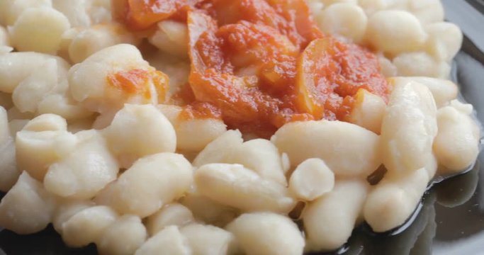 Fagioli bianchi con salsa al pomodoro piccante e cipolla su un piatto nero