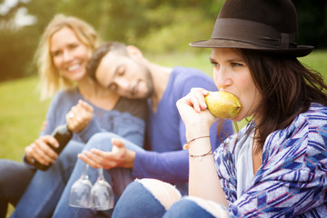 woman eating pear with friends at picnic