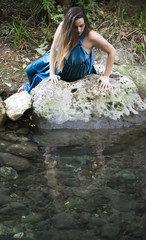 Beautiful woman on the bank of a mountain river with an evening dress