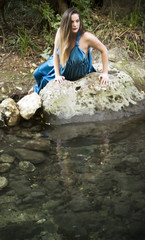Beautiful woman on the bank of a mountain river with an evening dress