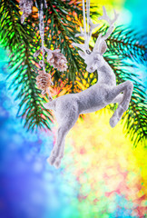 christmas vertical greeting card. Christmas Festive decoration in a shape white deer on xmas tree branch on rainbow color background with copy space