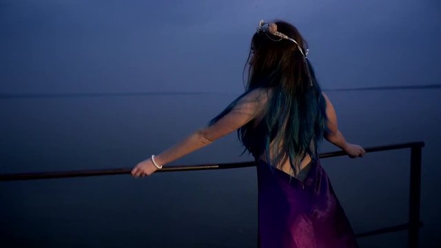 Mysterious girl with blue hair and feulette dress looks at the river