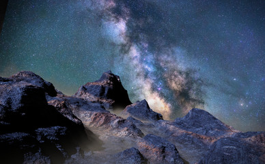 rocky landscape with low crawling fog lit by the Milky Way galaxy 