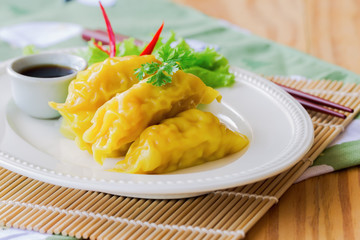 Homemade minced pork or shrimp dumpling on white plate served with dipping soy sauce on wood table so delicious and gppdness food for breakfast or lunch or dinner. Dim sum or dumpling is Chinese food.