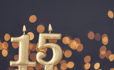 Gold number 15 celebration candle against blurred light background