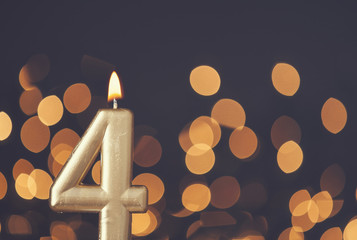 Gold number 4 celebration candle against blurred light background