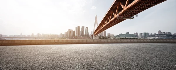 Foto op Plexiglas lege asfaltweg met moderne brug en gebouwen © zhu difeng