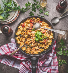 Tasty tortellini pasta pot with vegetables sauce and spoons on rustic kitchen table background with plates and cutlery, top view. Italian cuisine food concept