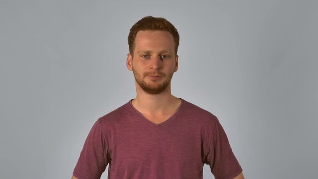 serious caucasian guy with red hair showing emotion hurt. handsome redheaded men wearing in casual t-shirt. Portrait ginger young caucasian man on grey background