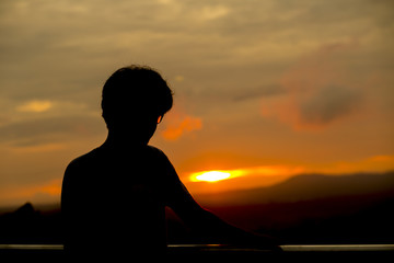Fototapeta premium A man standing on a mountain The sun is falling.