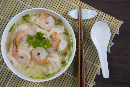 Very delicious shrimp wonton and minced pork soup (dumpling) in white bowl on wood table / Select focus image