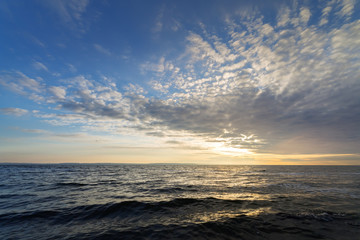 Fototapeta na wymiar sun in the clouds over a rough sea / rough sea summer landscape