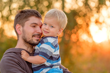 Father and son outdoor portrait in sunset sunlight