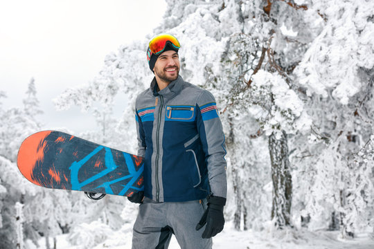 Smiling snowboarder holding board for snowboarding