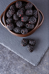 top view on blackberries in bowl on dark table background. © luckybusiness