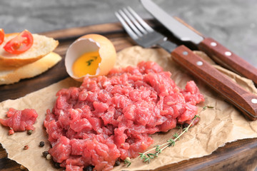 Delicious steak tartare with yolk on wooden board, closeup