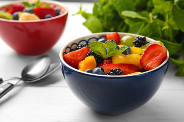 Bowl with delicious fruit salad on wooden table