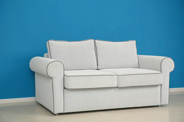 Comfortable sofa on color wall background