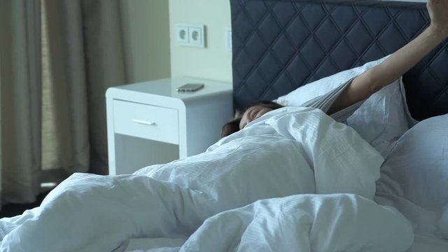 Happy woman waking up from sleep in bedroom and stretching arms, super slow motion 120fps
