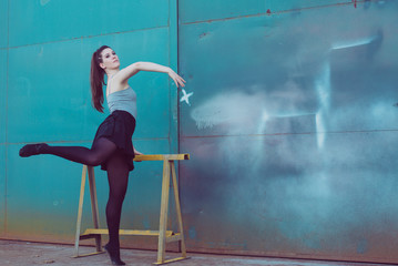 Fototapeta na wymiar Young ballerina in black clothes training in front of the turquoise blue door