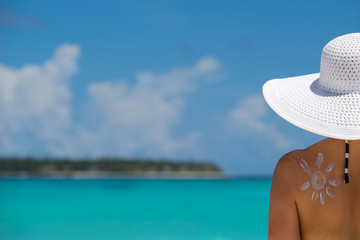 Woman with sun-shaped sun cream on beach