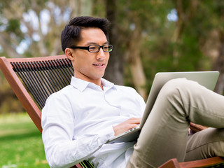 Young businessman using laptop while sitting outdoors