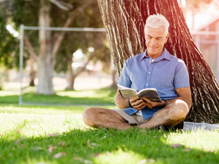 Senior man sittingin park while reading book