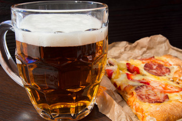 Light beer in glass and fragrant Italian pizza.
