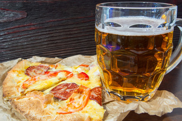 Light beer in glass and fragrant Italian pizza.