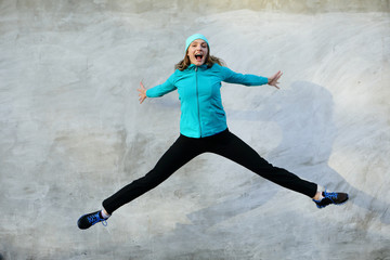 Sport background healthy jump, gray background, woman jumping sport outdoor, street, looking camera